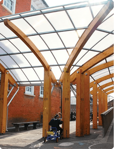 : Large custom timber beam architectural structure under a clear outdoor canopy.