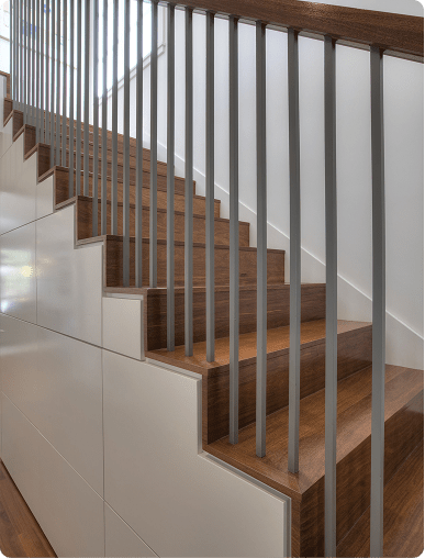Modern wooden staircase with dark metal railings built with custom closet design precision.